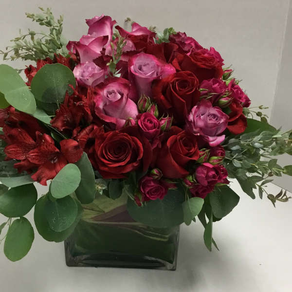 Bouquet of red and pink roses in a square glass vase