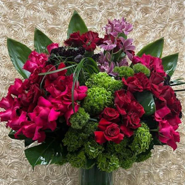 Bouquet of red and pink flowers in a tall glass vase