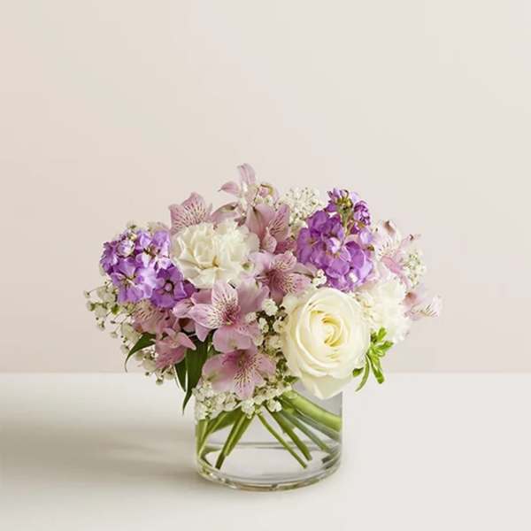 Bouquet of white roses and pink-purple flowers in a clear glass vase