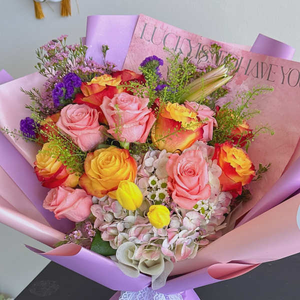 Bouquet of pink and yellow roses wrapped in lavender paper