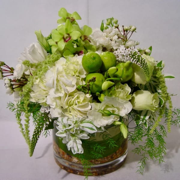 White and green floral arrangement in a glass vase with lime accents