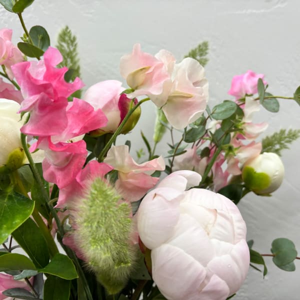 Pink and white flowers arranged with greenery in a bouquet
