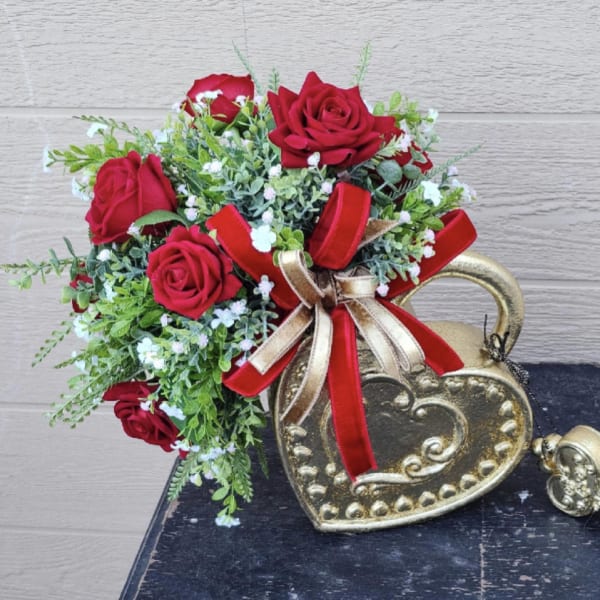 Red roses arranged in a gold heart-shaped container with ribbon.