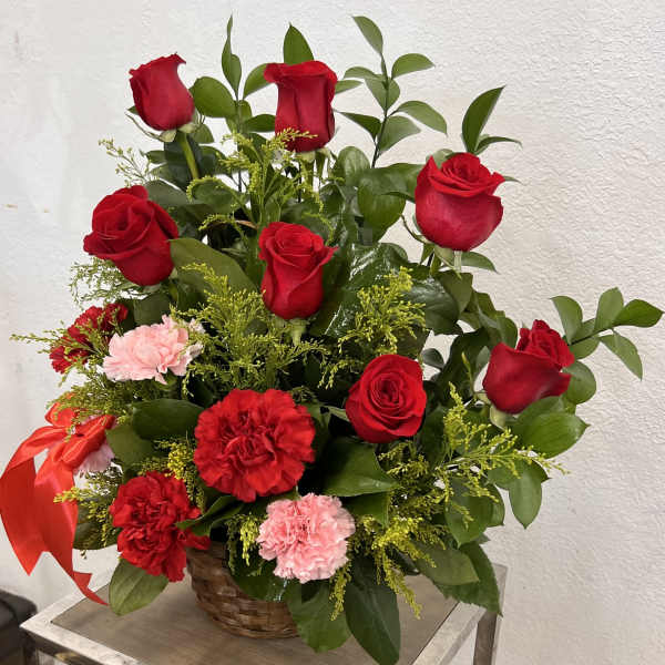 Basket arrangement of red roses and carnations with pink accents