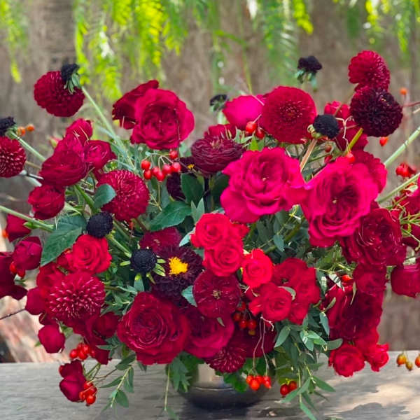 Red rose and dahlia arrangement in a dark vase