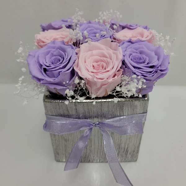 Pink and lavender roses in a silver square box with a purple ribbon