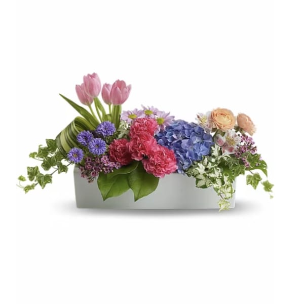 Mixed bouquet in a white rectangular container with pink tulips and blue hydrangea
