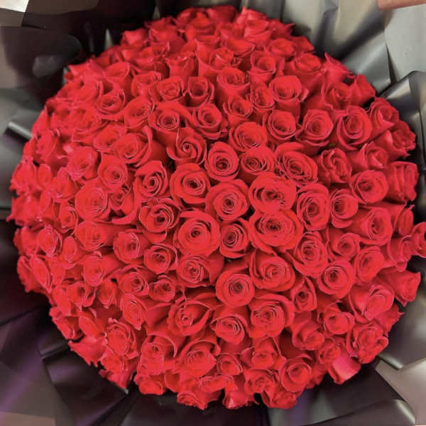 Large bouquet of red roses wrapped in dark paper