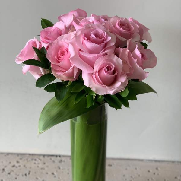 Pink roses arranged in a tall glass vase