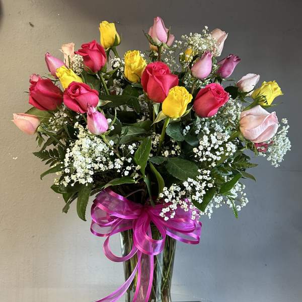Bouquet of multicolored roses in a clear glass vase with a pink ribbon