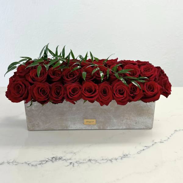 Long rectangular box filled with red roses and greenery