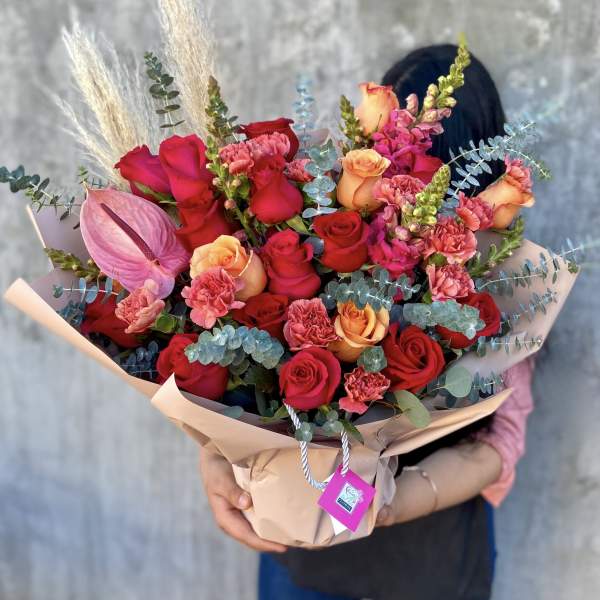 Bouquet of red and peach roses with pink carnations and an anthurium