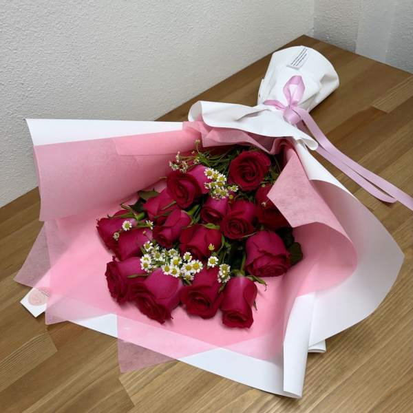 Bouquet of red roses wrapped in pink and white paper with a ribbon