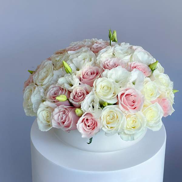 Round bouquet of pink and white roses on a white pedestal