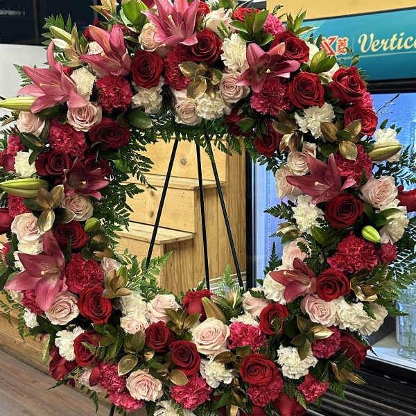 Large floral wreath with red, pink, and white blooms on a black stand