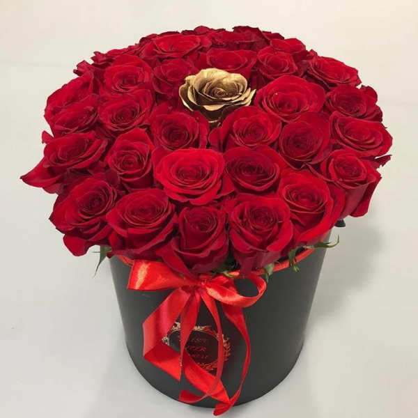 Red roses arranged in a black hatbox with a red ribbon