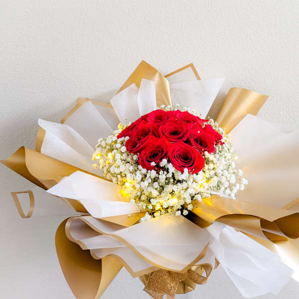 Bouquet of red roses wrapped in white and gold paper