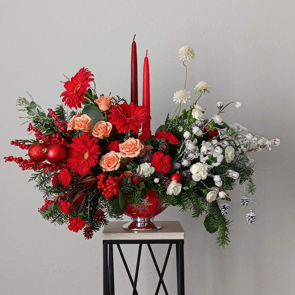 Red and white floral centerpiece with candles in a red vase