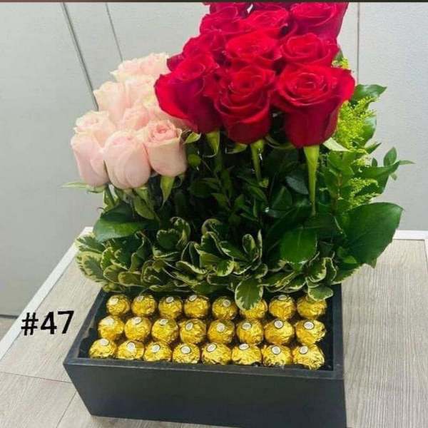 Red and pale pink roses in a black box with gold-wrapped chocolates