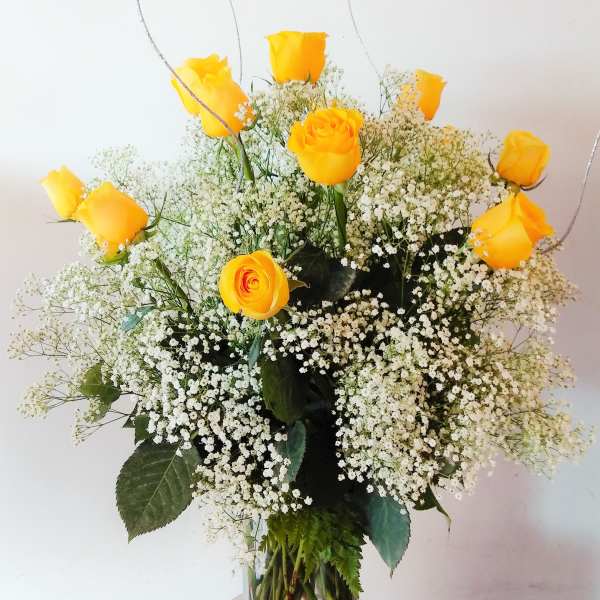 Yellow roses in a clear glass vase with white baby's breath
