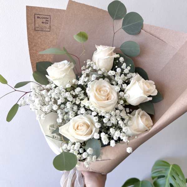 Bouquet of white roses with baby's breath and eucalyptus in brown paper