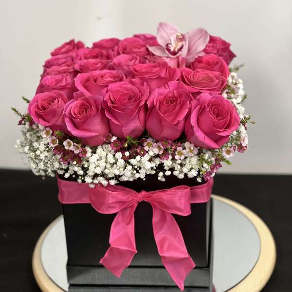 Hot pink roses arranged in a black box with a pink ribbon