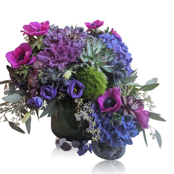 Purple and blue floral arrangement with succulents in a dark vase
