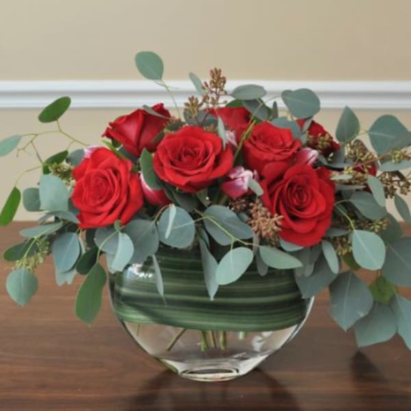 Red roses in a glass vase with eucalyptus
