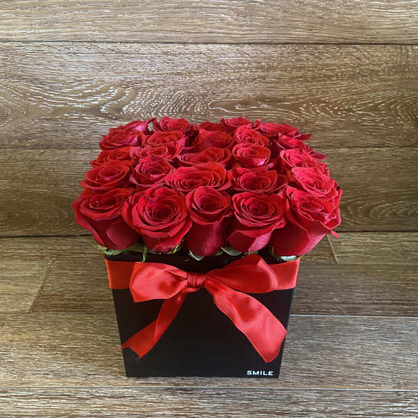 Red roses arranged in a black square box with a red ribbon