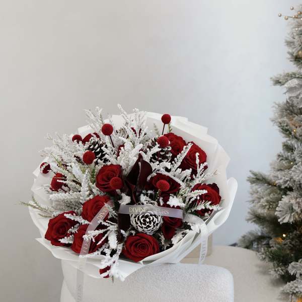 Bouquet of red roses with frosted white accents and pinecones