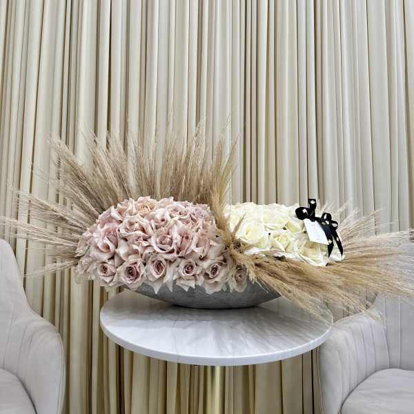 Two rose arrangements with pampas grass on a round table