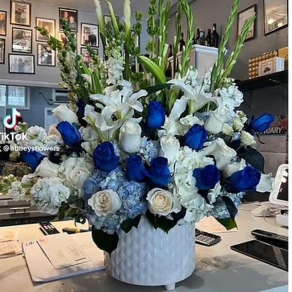 Large blue and white floral arrangement in a white vase