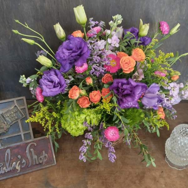 Mixed bouquet of purple, pink, and orange flowers in a basket
