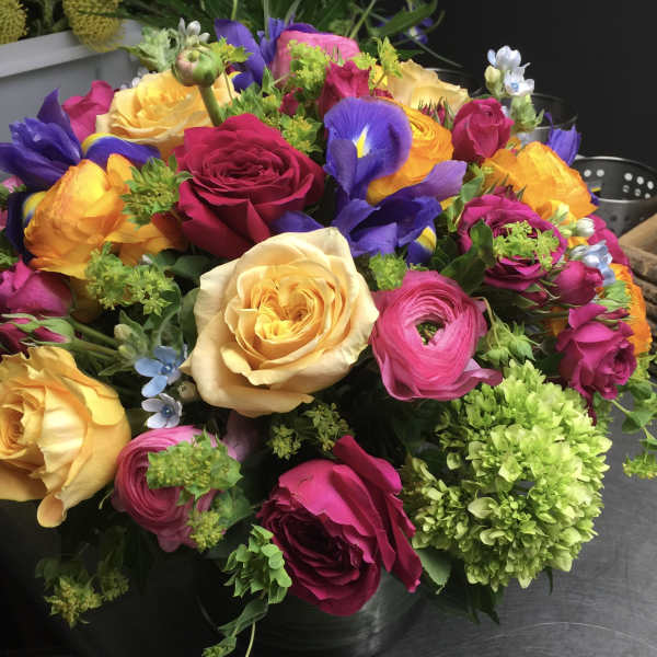 Colorful bouquet of roses, ranunculus, and irises in a vase