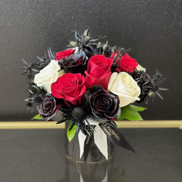 Bouquet of red, white, and black roses in a glass vase
