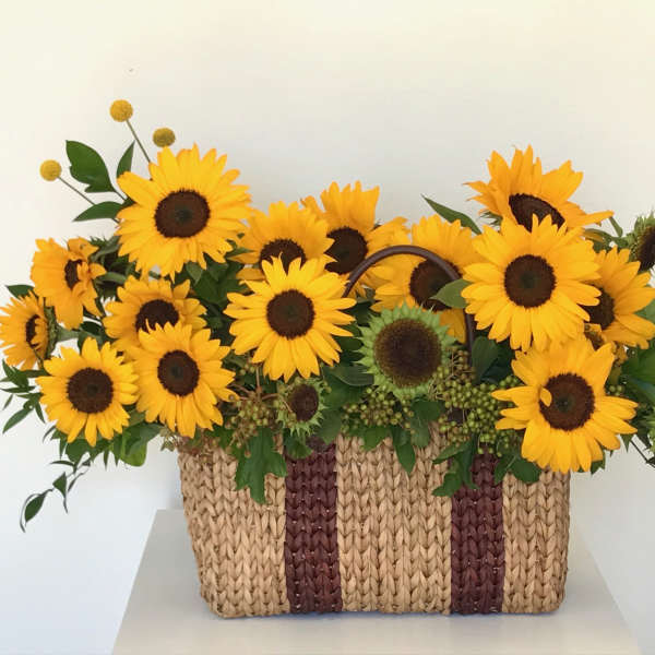 Basket of bright yellow sunflowers with dark centers