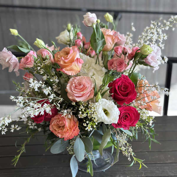 Mixed bouquet of pink, peach, and white roses in a glass vase