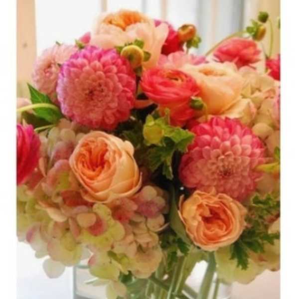 Pink and peach flowers arranged in a clear glass vase