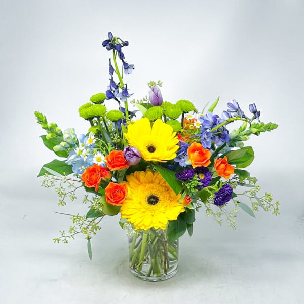 Mixed bouquet in a clear glass vase with yellow gerberas and orange roses