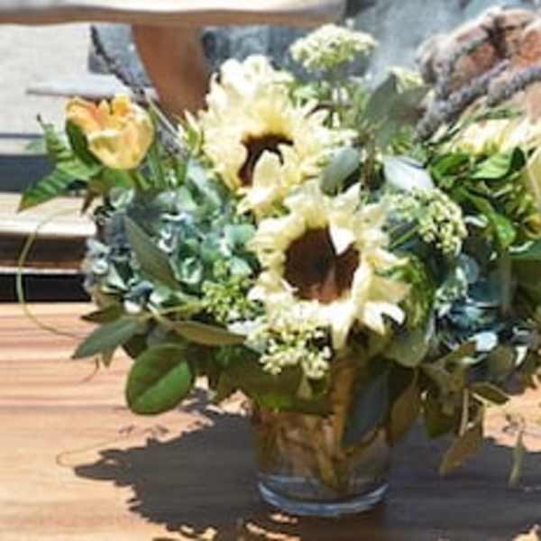 Bouquet of sunflowers and pale yellow tulips in a glass vase