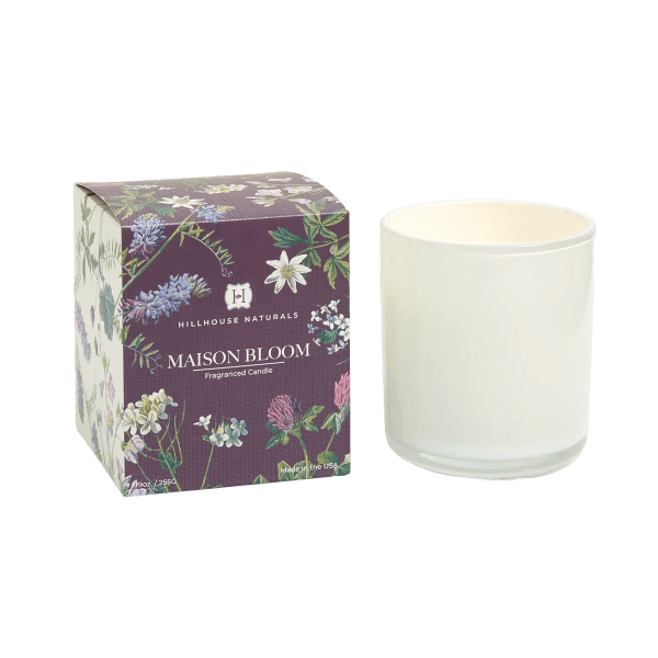 White glass jar candle beside a floral-printed Maison Bloom box