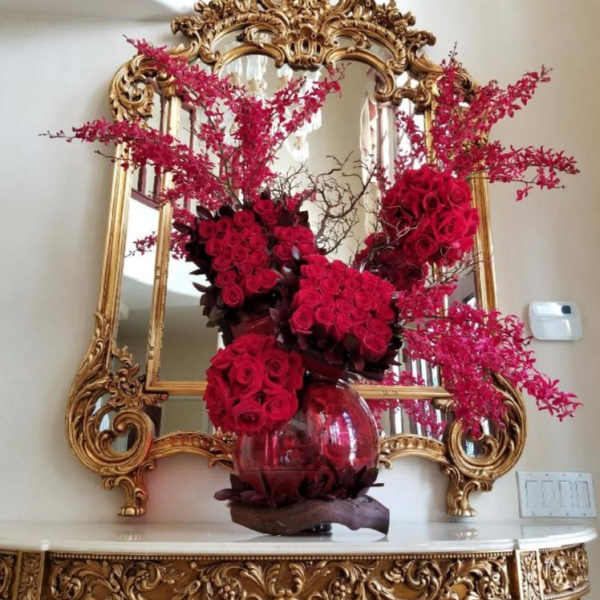 Red rose arrangement in a glass vase with pink branching accents