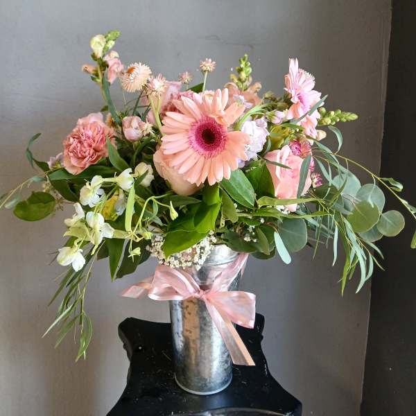 Pink and peach mixed bouquet in a metal vase with a pink ribbon