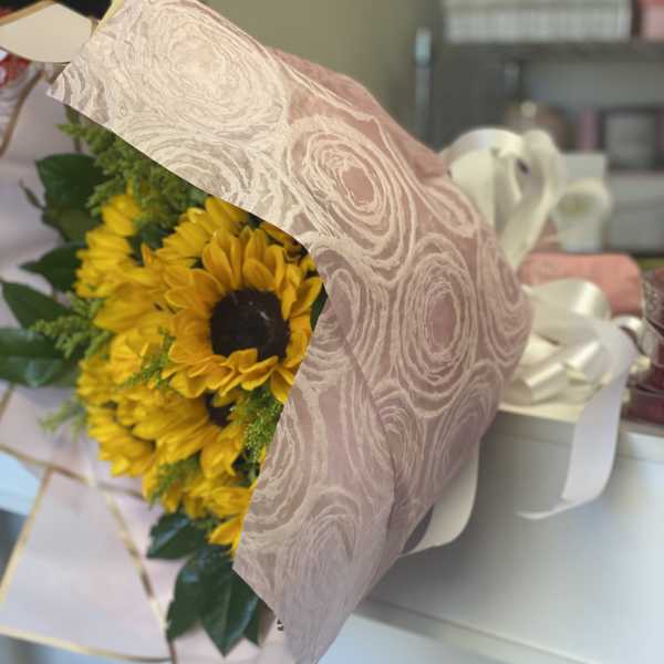 Bouquet of yellow sunflowers wrapped in pink patterned paper