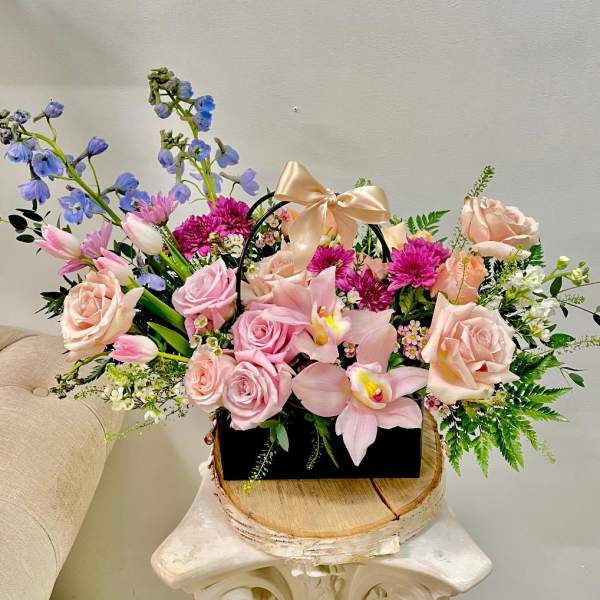 Mixed pink and blue flower arrangement in a black handled box with a satin bow