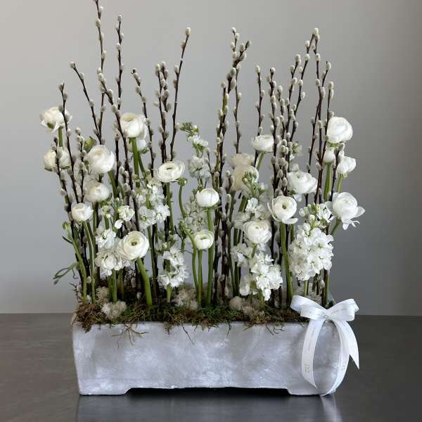 White floral arrangement with tall pussy willow branches in a rectangular container