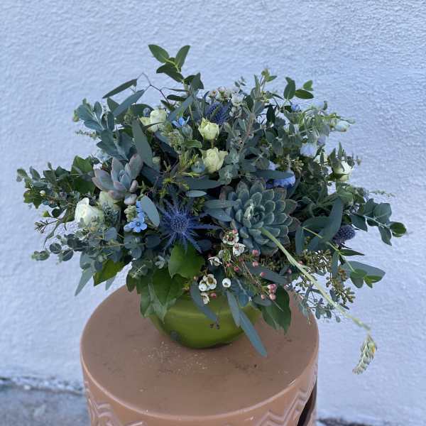 Mixed bouquet with succulents and small white flowers in a green vase