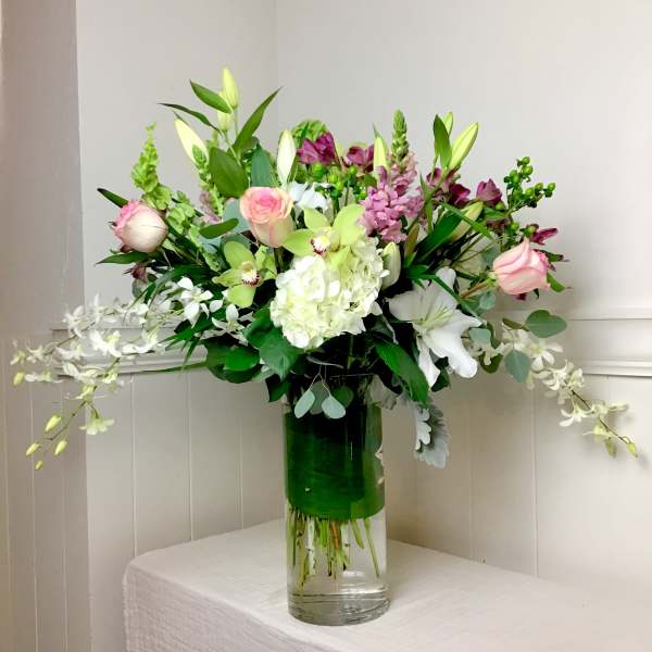 Mixed bouquet in a clear glass vase with pink, white, and green flowers