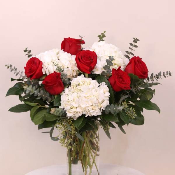 Red roses and white hydrangeas in a clear glass vase