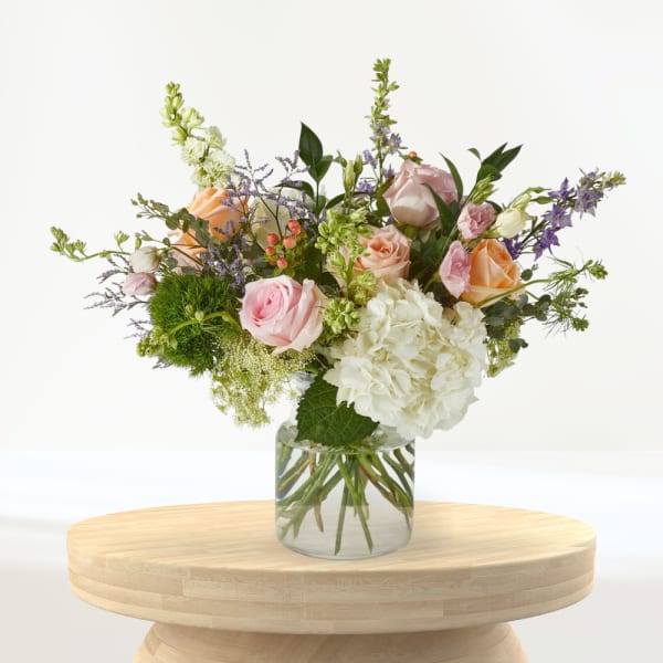 Bouquet of pink, peach, and white flowers in a clear glass vase